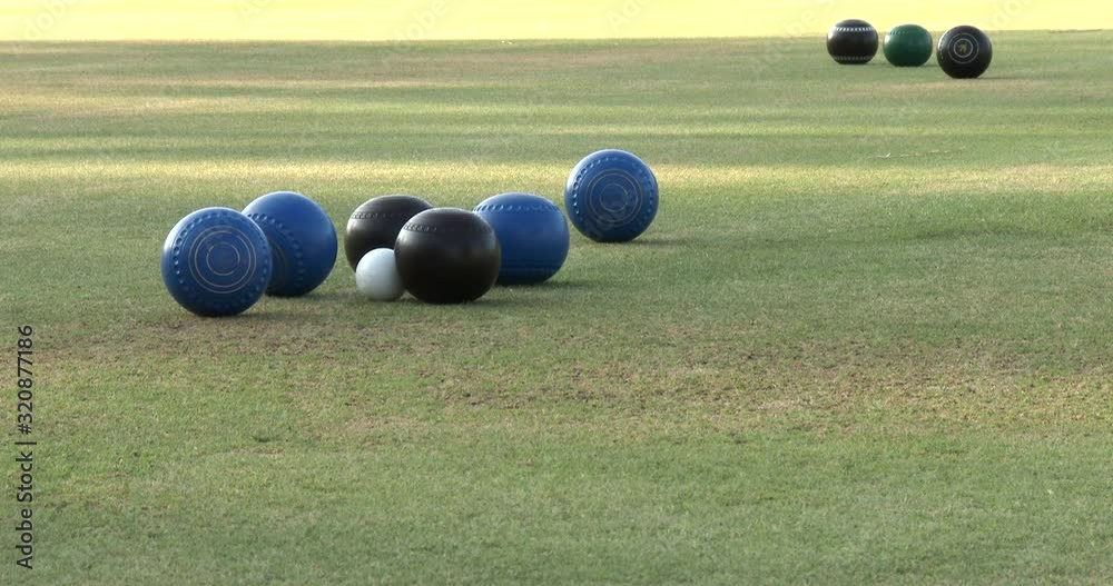 Close up of balls coming to rest next to the jack in competition lawn bowls