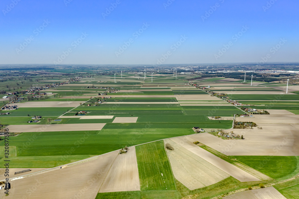 Beautiful top view of plowed and sown fields.You can see windmills on the horizon, villages and arable land that create a bizarre pattern on the ground. Shot on drone. 