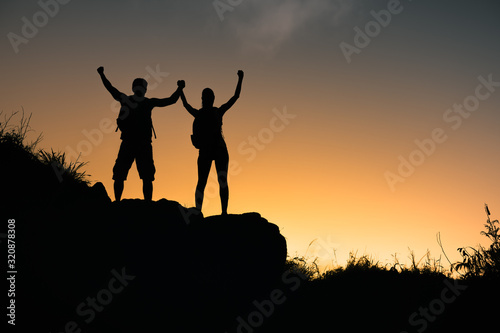 Man and woman celebrating climb to the top of mountain. 