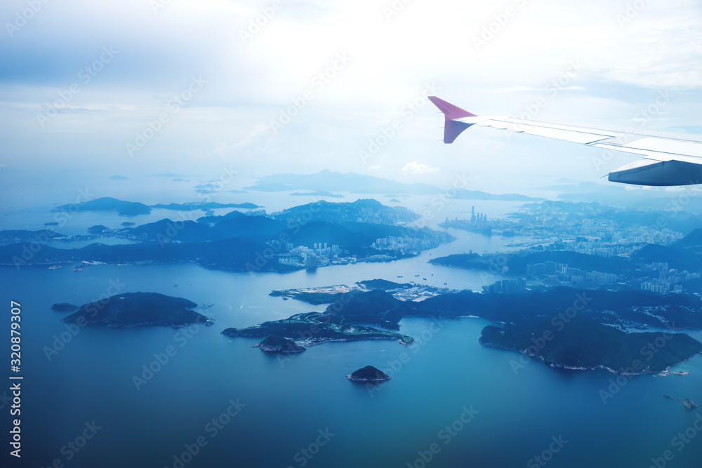 Aerial view of Hong Kong islands in blue morning mood from a flying airplane with wing Aerial view of Hong Kong islands in blue morning mood from a flying airplane with wing