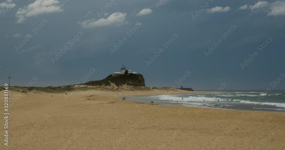 Pan up from the footprints in the sand to the ocean waves crashing and the dark gloomy skies as a storm rolls in over Nobbys Beach, Newcastle, Australia Pan up from the footprints in the sand to the ocean waves crashing and the dark gloomy skies as a storm rolls in over Nobbys Beach, Newcastle, Australia