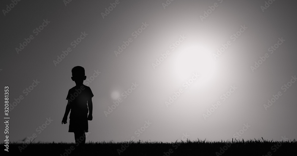 Silhouette of little boy standing in a grass field. Silhouette of little boy standing in a grass field.