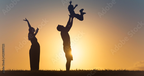 Family silhouette in the park having fun, and father throwing son up in the air.