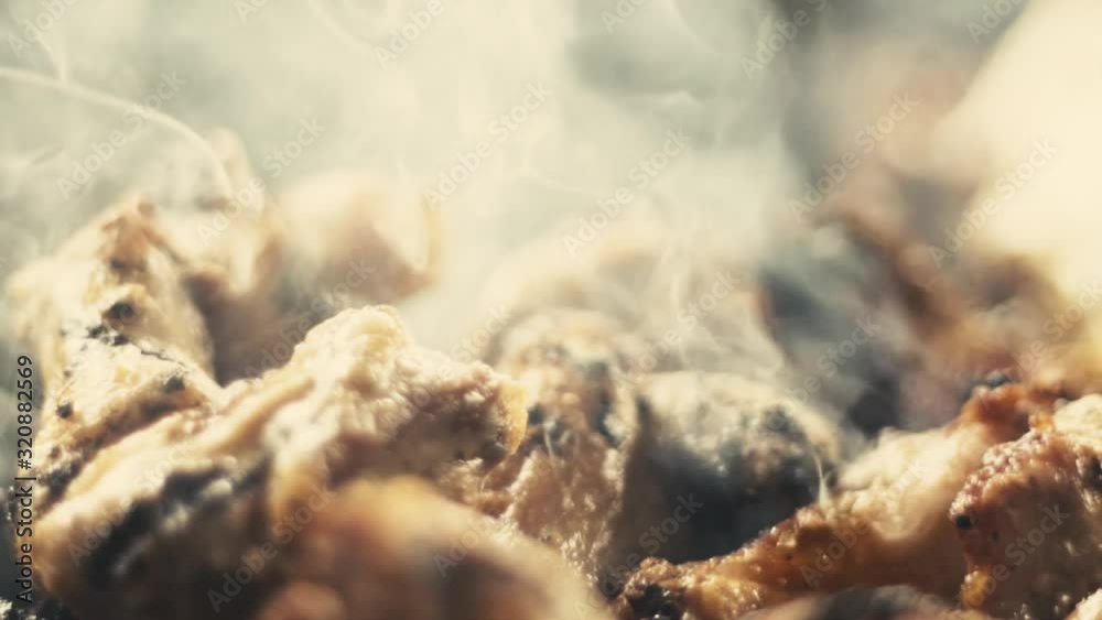 Slow motion close-up shot of chicken wings and smoke from the charcoal grill