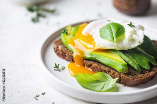 Leinwand Poster Healthy breakfast whole wheat toasted bread with avocado and poached egg over wh