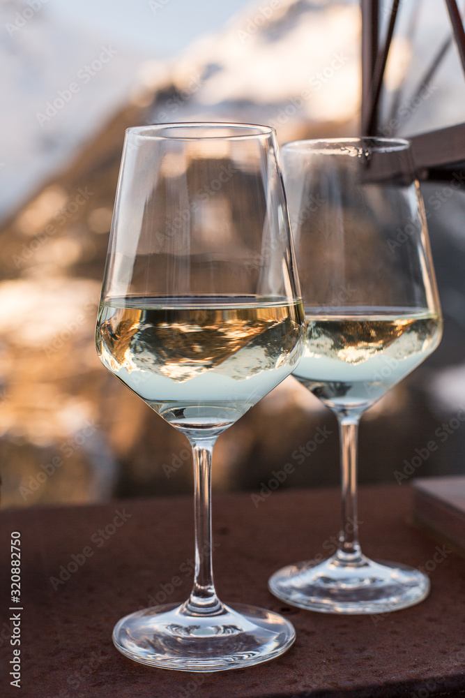 Two glasses with white wine and reflections of mountains. Italian Alps.