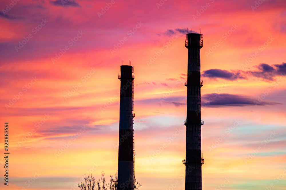 Pipes of a power plant against the sunset sky