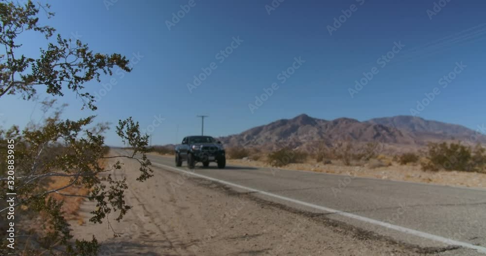A close up shot of a desert plant on the side of the road as a truck passes by. Shot in 4k resolution.