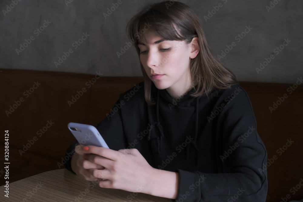 Young pensive woman waiting for call on her cell telephone Young pensive woman waiting for call on her cell telephone