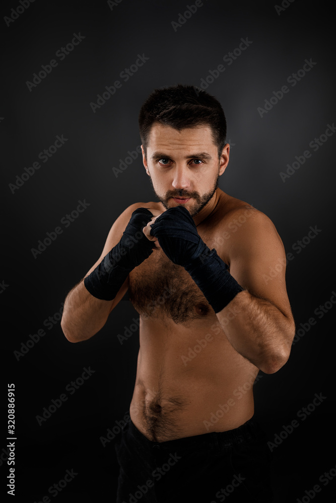 Muscular boxing man ready to fight on black background
