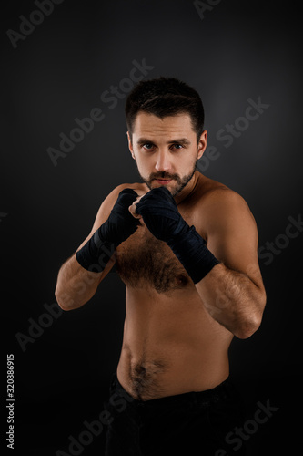 Muscular boxing man ready to fight on black background © producer