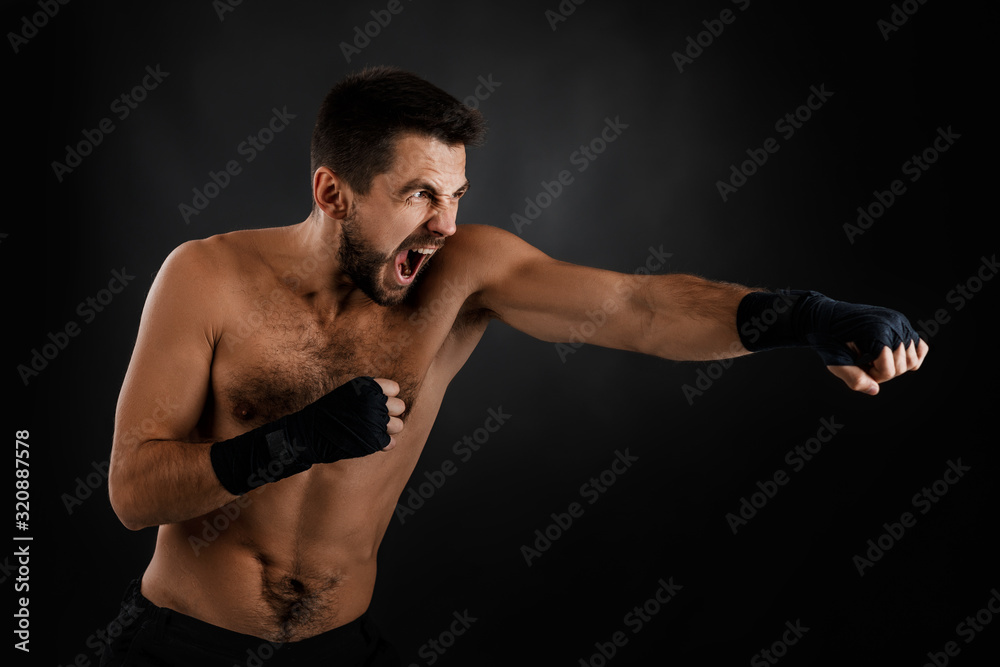 Sportsman boxer throwing a fierce and powerful punch. muscular man on black background.