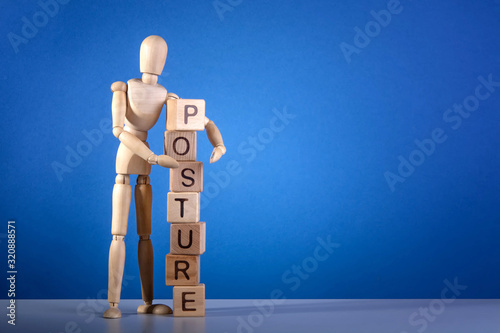 Wooden mannequin near the tower of cubes with the inscription Posture on blue background