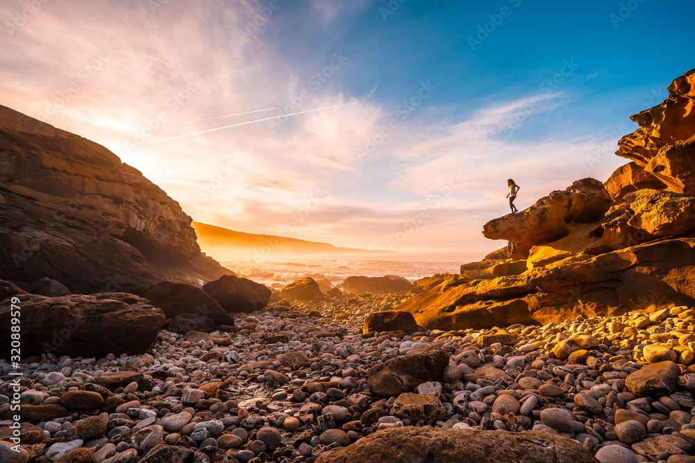 A young woman enjoying the Orange Sunset on the coast of Mount Jaizkibel near San Sebastian, Gipuzkoa. Spain