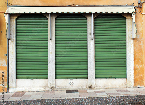 Old closed green metal rolling shutters on an old building