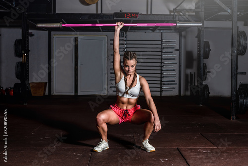 Fotografi Young beautiful attractive muscular and strong fit girl holding heavy barbell we