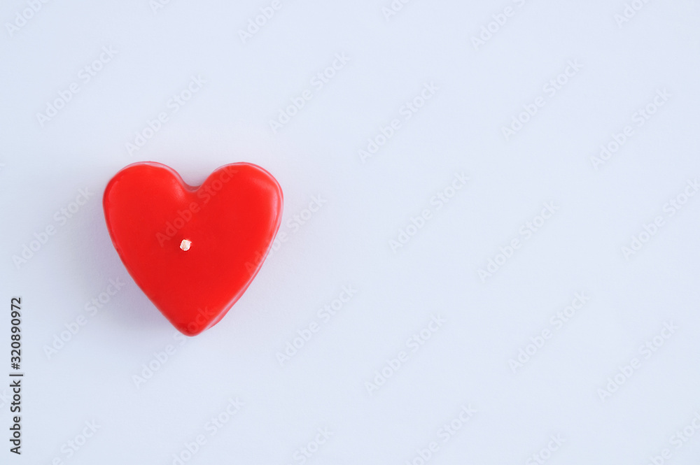 Red candle heart symbol on white background close-up.