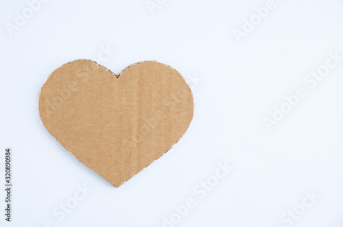 Heart symbol made of brown cardboard with jagged edges on white background.