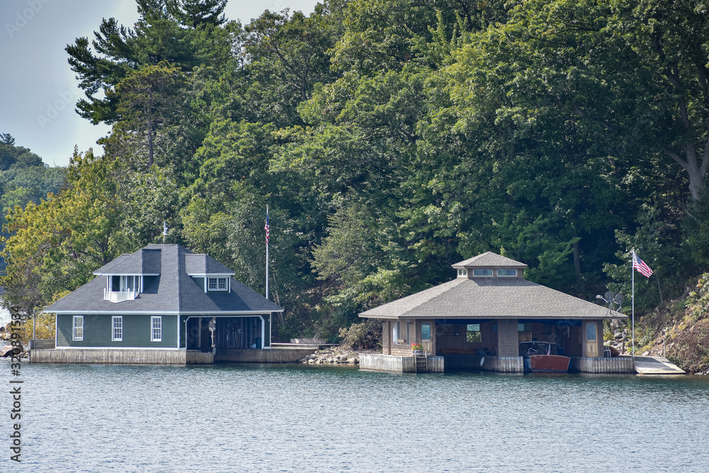 Naklejka premium Different buildings in a rocky area on the coast of a lake during daytime, and surrounded by trees. Real State concept. Thousands Islands. Ontario, Canada.