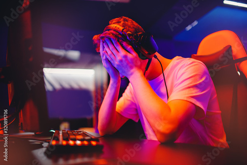 Tela Gamer young man is defeated in online video game, anger and facepalm, screaming and emotion, neon color
