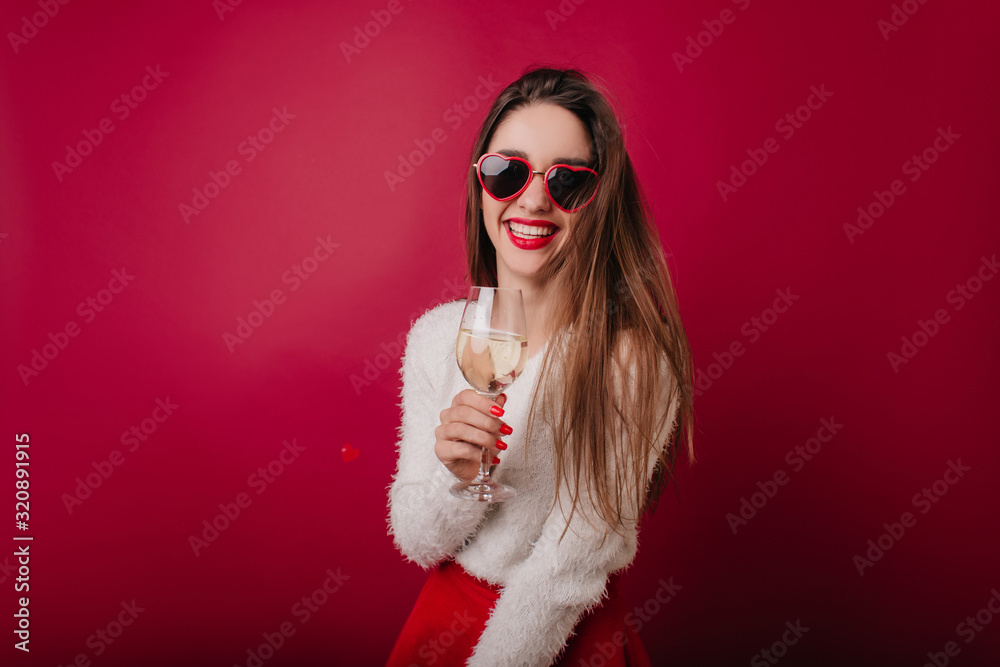 Graceful lady in funny glasses celebrating something. Romantic european woman in white sweater drinking wine in studio. Graceful lady in funny glasses celebrating something. Romantic european woman in white sweater drinking wine in studio.