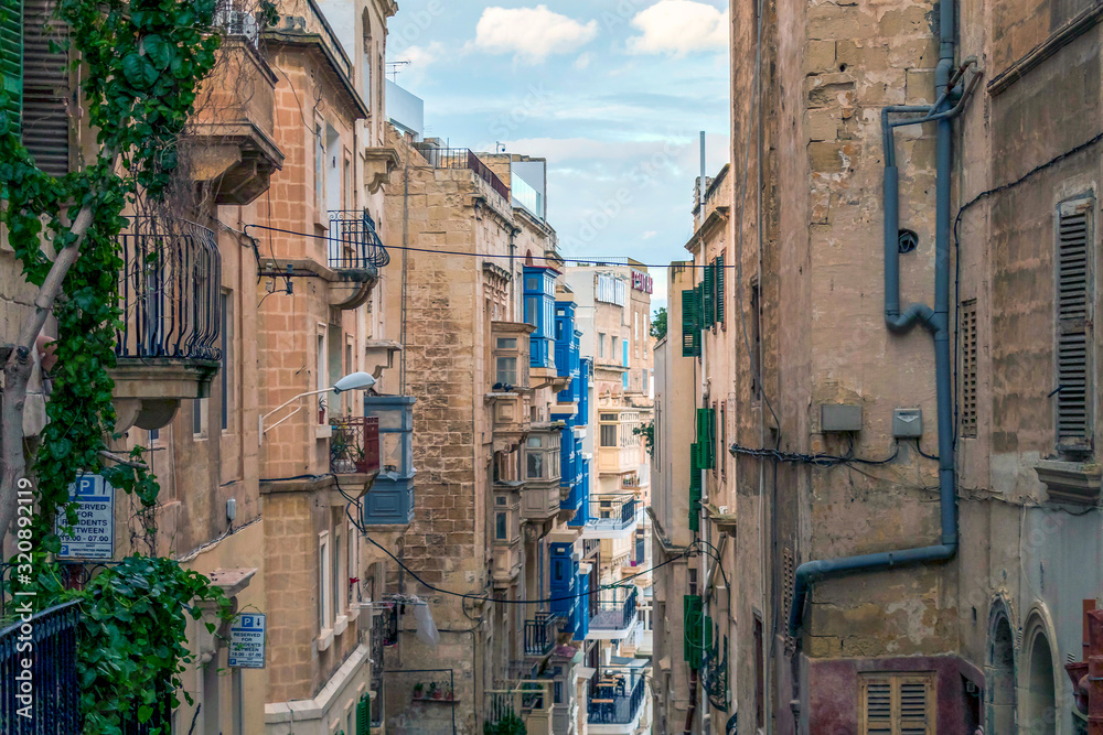 Typical narrow streets with colorful balconies at traditional buildings in Valletta, capital of island of Malta, Europe