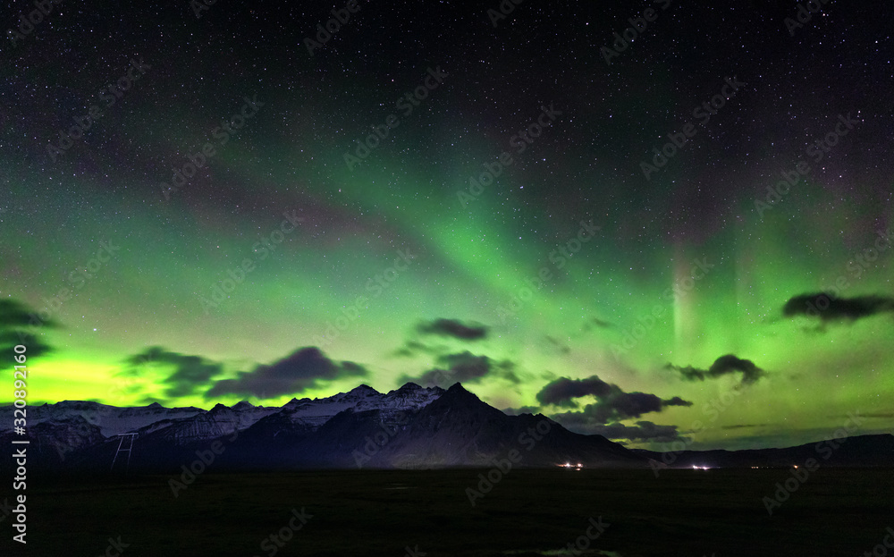 The Aurora Borealis, or Northern Lights over the mountains of Iceland