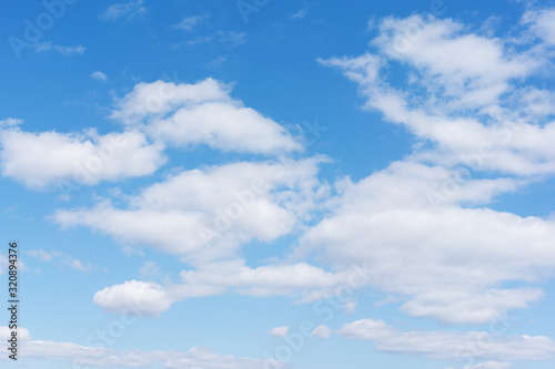 White cumulus clouds against the background against blue on a blue background.