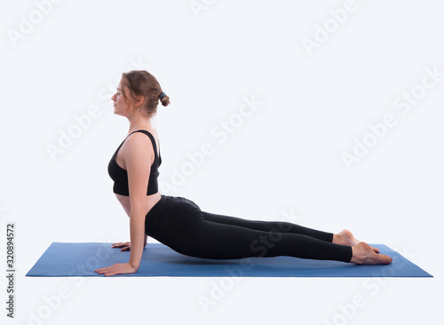 Portrait of gorgeous young woman practicing yoga indoor. Beautiful girl practice cobra asana in studio on white background.Calmness and relax, female happiness.