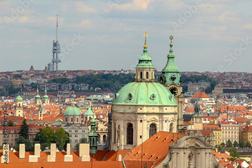 Dome and clock tower of old baroque St. Nicholas Church (Malá Strana) of 18th century. Roofs of houses and buildings of Prague. Skyline with a television tower.