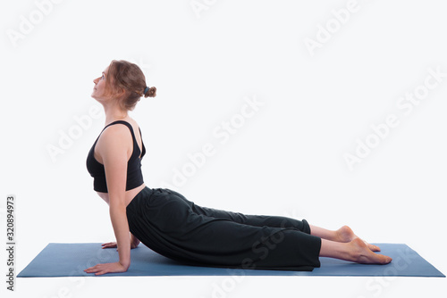 Portrait of gorgeous young woman practicing yoga indoor. Beautiful girl practice cobra asana in studio on white background.Calmness and relax, female happiness.