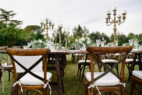 Decorated with floral compositions wedding celebration table with brown chiavari chairs guests seats outdoors in the gardens photo