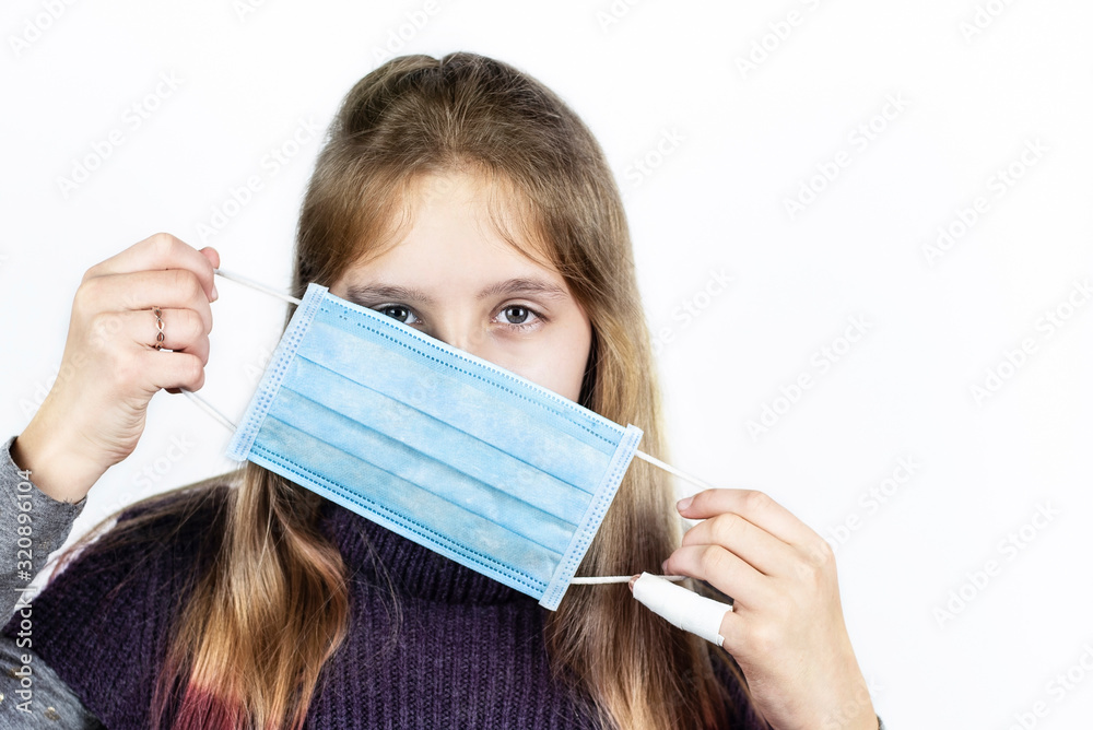 Medical mask on the face of a teenager girl. The girl puts on a mask to prevent colds and viruses Medical mask on the face of a teenager girl. The girl puts on a mask to prevent colds and viruses
