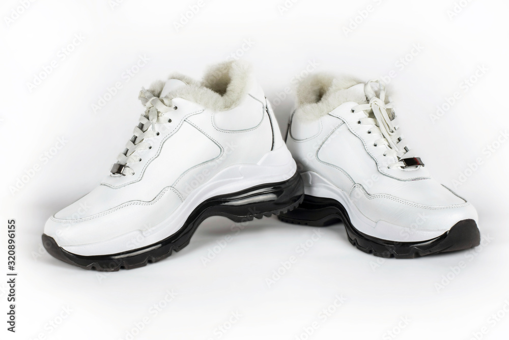 White warm women's sneakers on a light background. Such shoes are warm and comfortable to walk long distances in the cold seasons