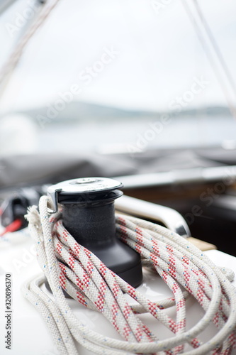 Close up detail of winch windlass with coiled up halyard rope on sail boat