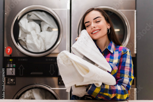 Slika na platnu Girl enjoys clean and smelling towels after washing in launderette