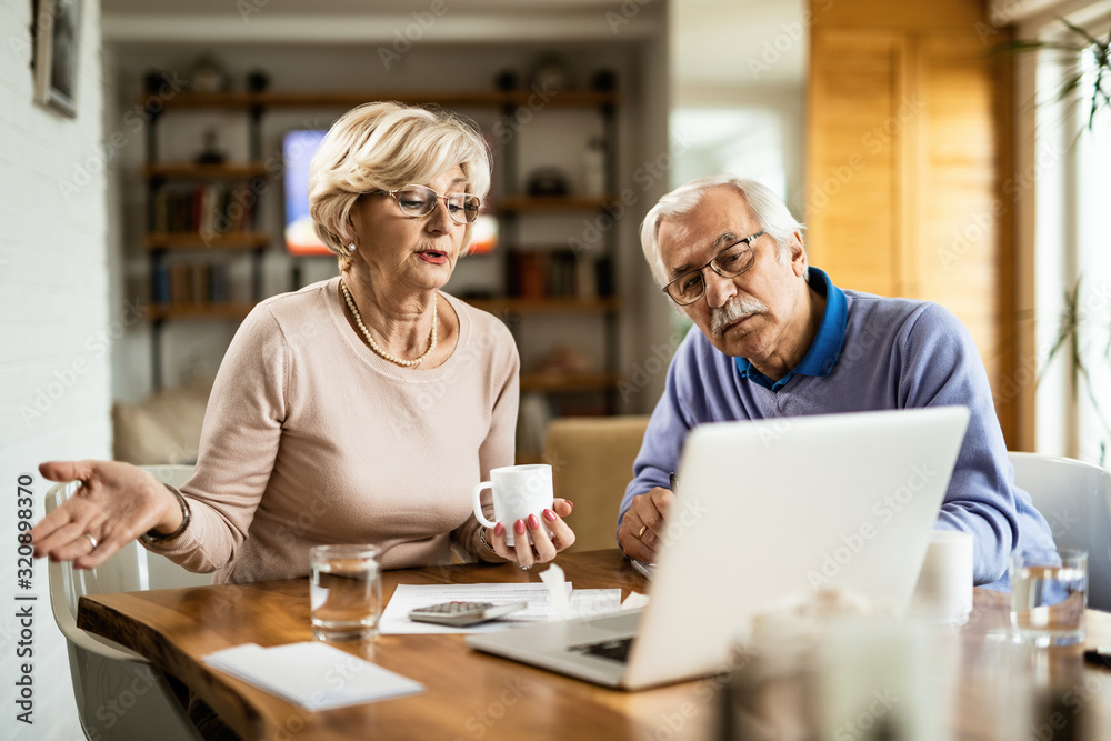 Senior couple using laptop while going through home finances. Senior couple using laptop while going through home finances.
