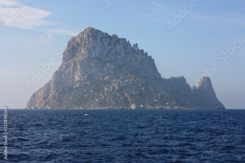 the islet of Es Vedra among the mist on the blue water of the ibiza sea photo