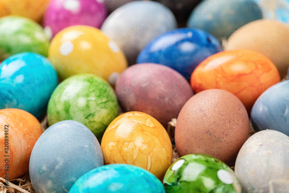 Different easter eggs with straw on wooden plate on green table Different easter eggs with straw on wooden plate on green table