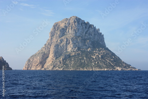 the islet of Es Vedra among the mist on the blue water of the ibiza sea © Alessia