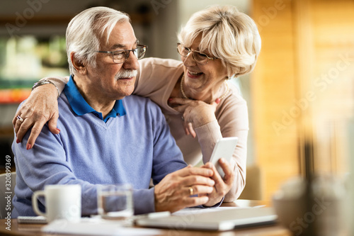 Happy senior couple using smart phone at home.