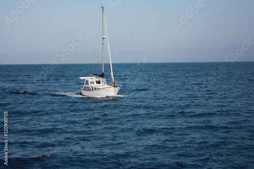 a white sailboat soaking in the summer blue water of the Mediterranean sea