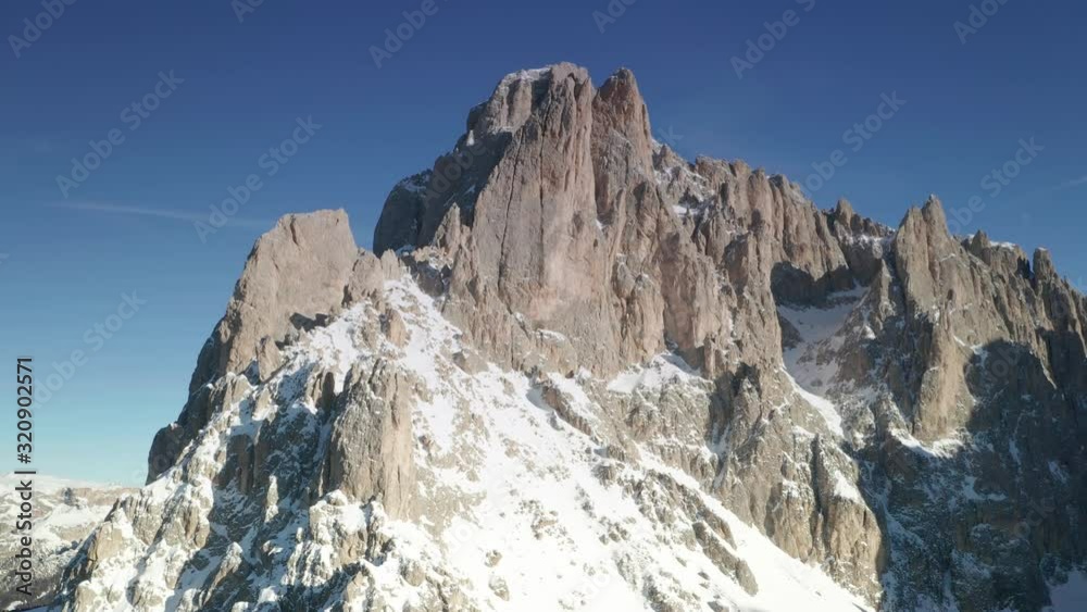 Aerial panning left view of a snow covered mountain and a valley. Flying close to Sassolungo mountain in Val Gardena, South Tyrol, Italian Dolomites. Aerial panning left view of a snow covered mountain and a valley. Flying close to Sassolungo mountain in Val Gardena, South Tyrol, Italian Dolomites.