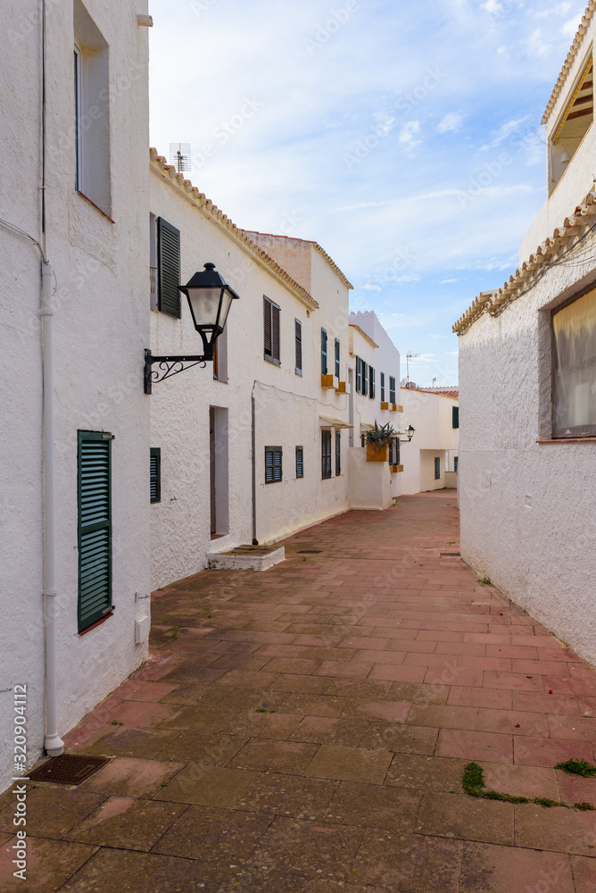 Narrow street with white architecture of Binibeca Nou, a traditional Spanish fishing village in Menorca. Spain