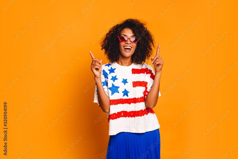 Happy young woman with national flag of USA at t-shirt pointing up. gesture and people concept - smiling student pointing, horizontal, copy space.