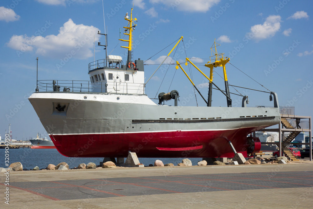Fototapeta premium old fishing boat on postament as tourist attraction in Latvia, Ventspils
