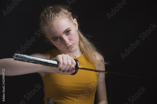 A beautiful young girl with a Japanese sword in her hands, a blonde in round dark glasses with a cold weapon in her hands