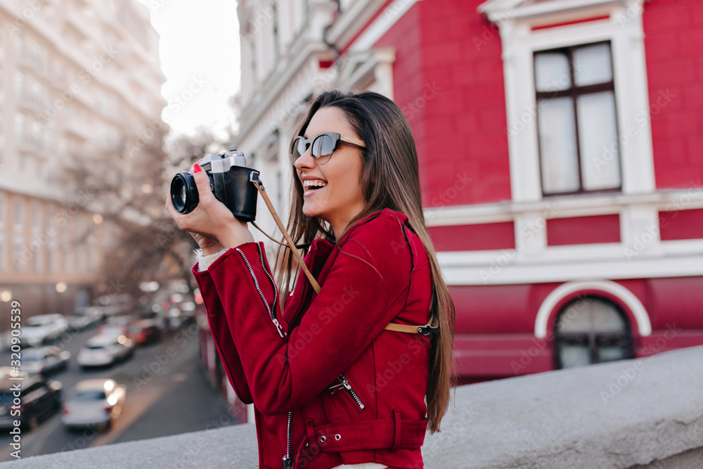 Charming girl with long straight hair taking picture of town. Laughing interested white lady with camera have a good time outdoor. Charming girl with long straight hair taking picture of town. Laughing interested white lady with camera have a good time outdoor.