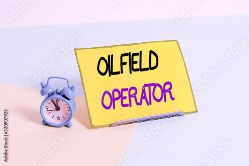 Text sign showing Oilfield Operator. Business photo showcasing responsible for optimizing production of the oil wells Mini size alarm clock beside a Paper sheet placed tilted on pastel backdrop