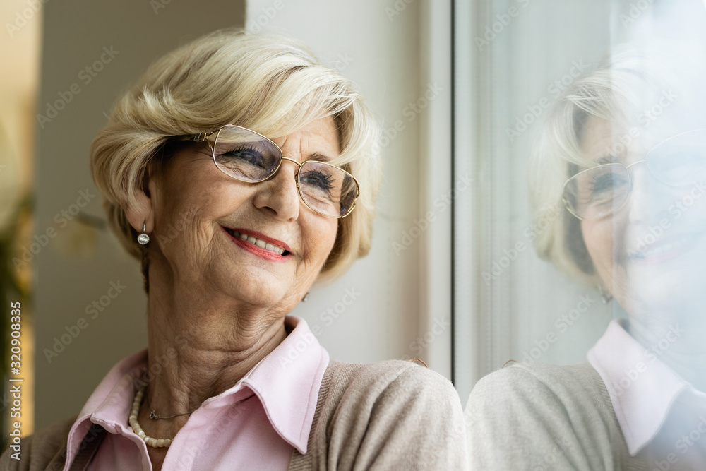 Smiling pensive senior woman relaxing by the window. Smiling pensive senior woman relaxing by the window.